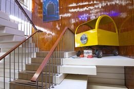 A round, yellow moblr concept car displayed in an office stairwell