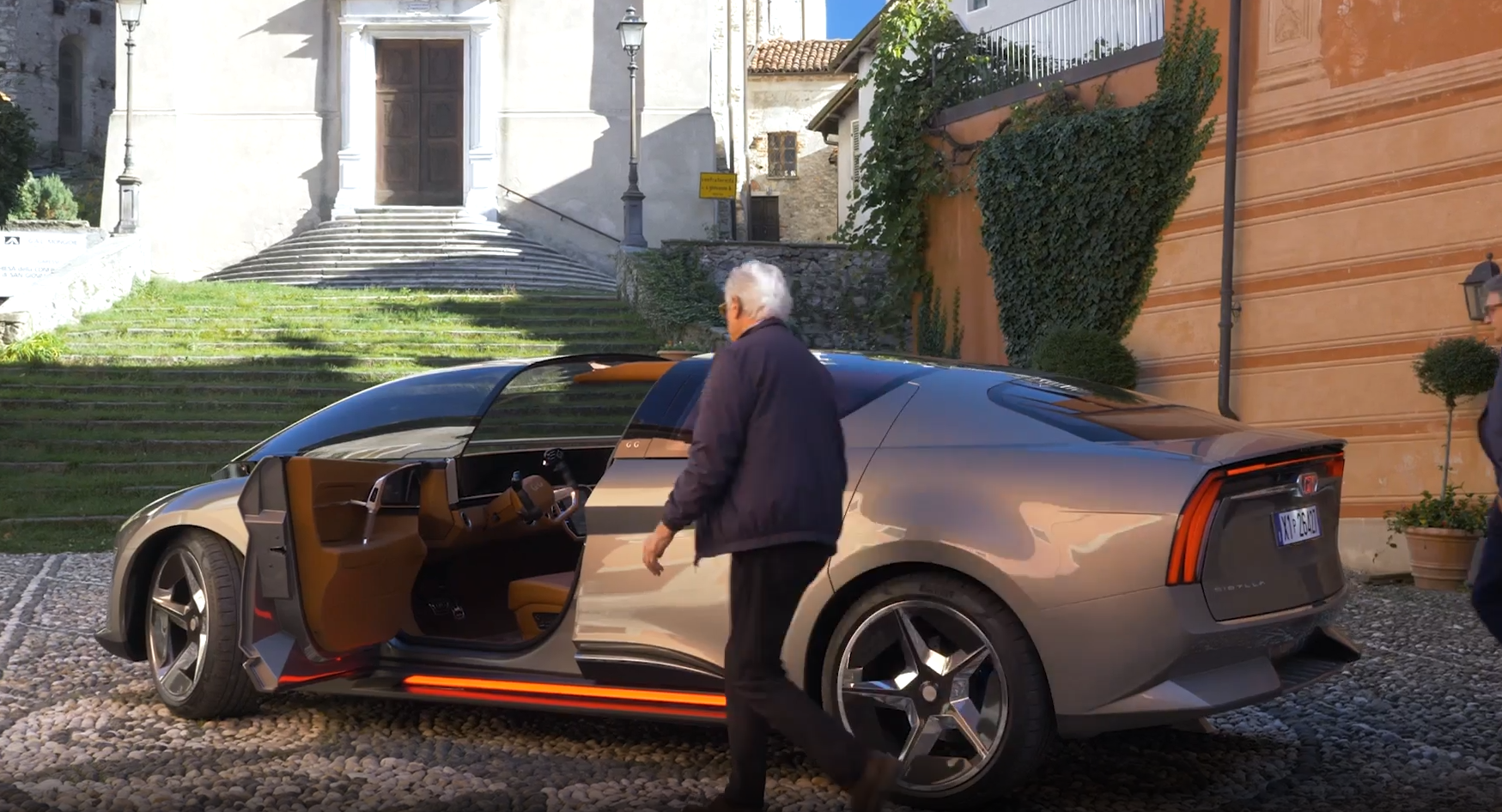 Rear three-quarter view of the Giugiaro Sibylla GG80 with a person approaching the open door